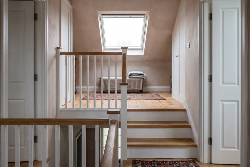 A short timber stairs with oak treads, white risers and spindles rising to an attic room under a roof window