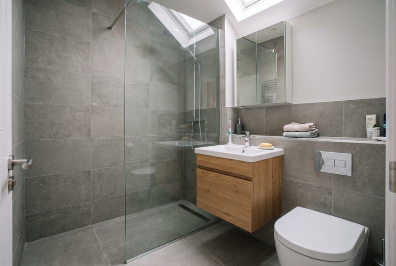 A shower room with a walk-in shower and glass screen, a wall-hung oak vanity unit and a mirror cabinet