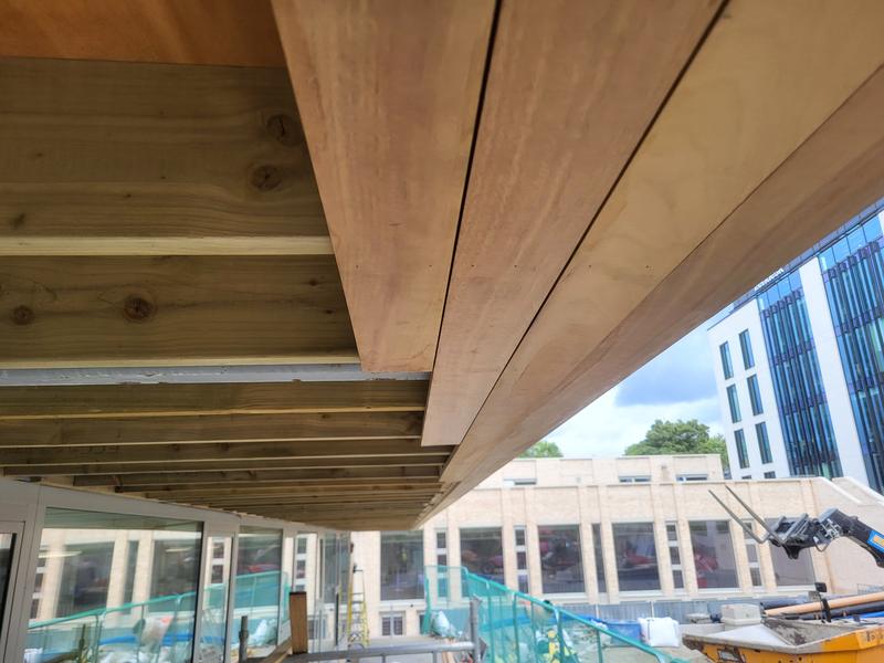 Close view of hardwood soffit boards being fixed under a large canopy