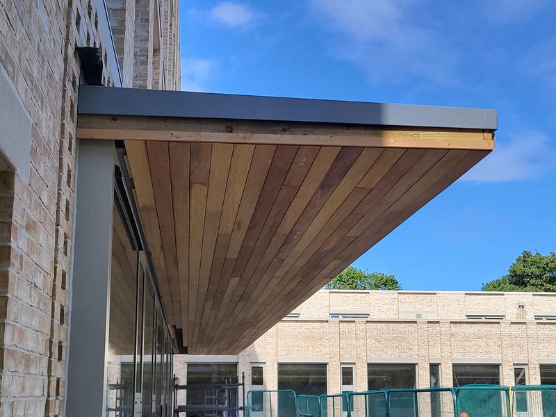 A finished hardwood soffit under a canopy, seen from below against a blue sky