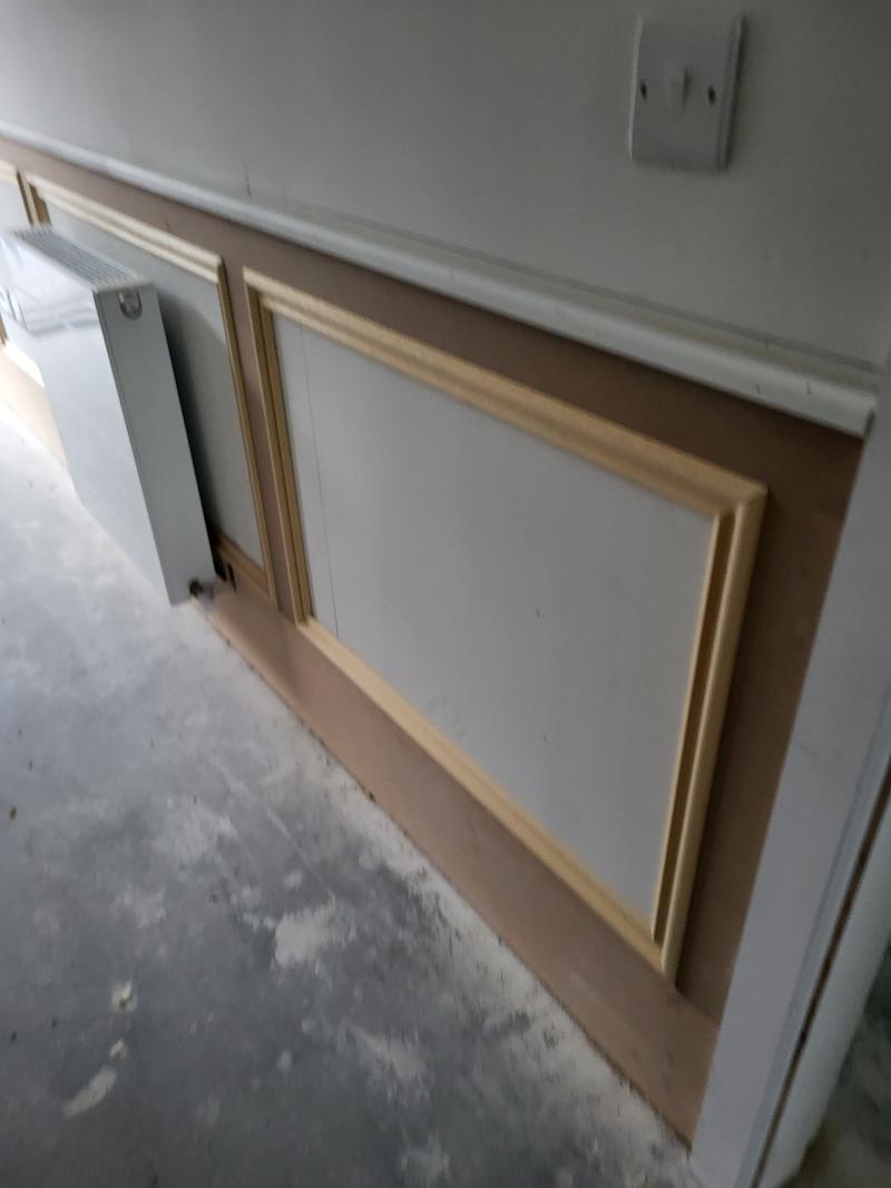 MDF wall panelling with raised frame panels along a room wall, unpainted, before the decorator