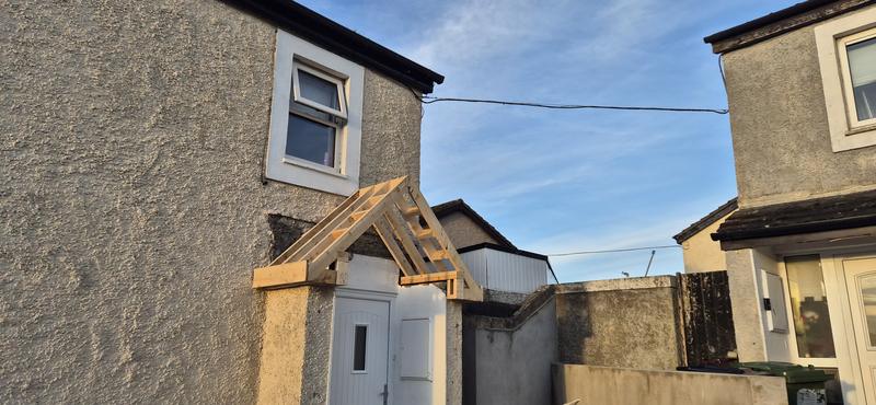 A new timber porch canopy frame over the front door of a house